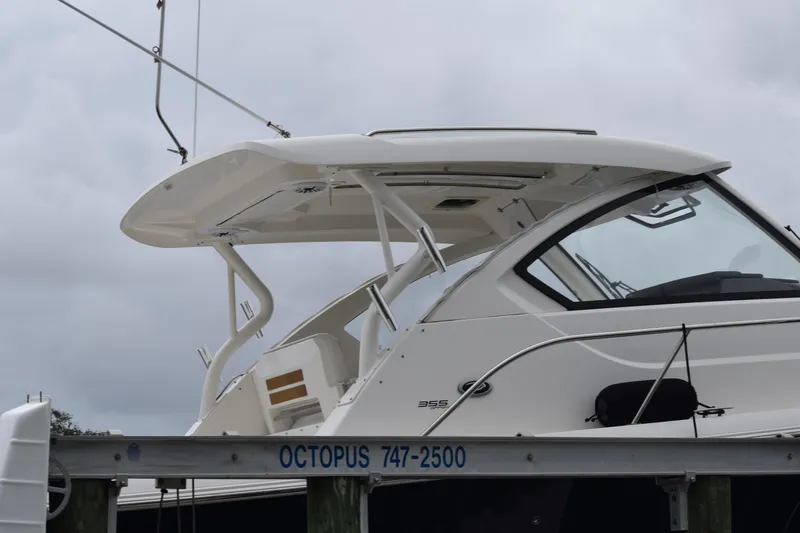 Slide: The Image of 2022 Pursuit OS 355 Offshore boat on a lift, side view under cloudy sky. - 455
