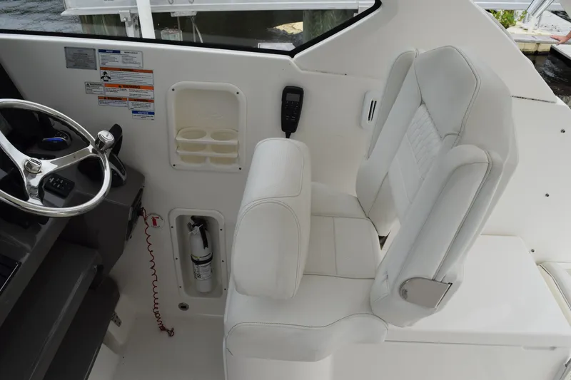 Slide: The Image of 2022 Pursuit OS 355 Offshore helm with white captain's seat and steering wheel. - 250