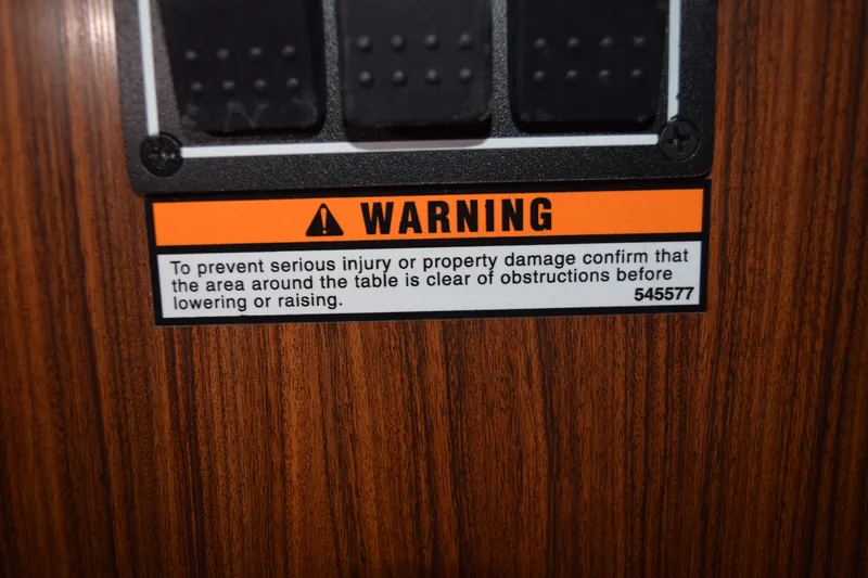 Slide: The Image of Warning label on 2022 Pursuit OS 355 Offshore, cautioning against obstructions near table. - 372