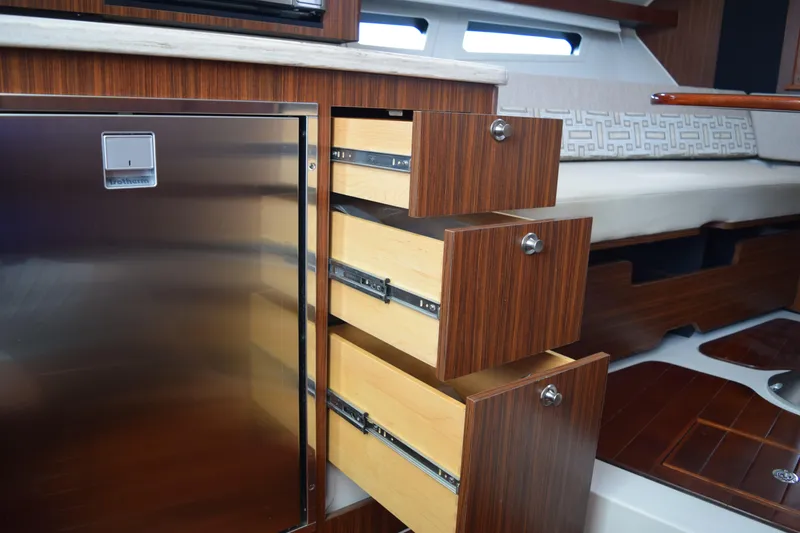 Slide: The Image of Interior of 2022 Pursuit OS 355 Offshore with open wooden drawers and stainless steel fridge. - 425
