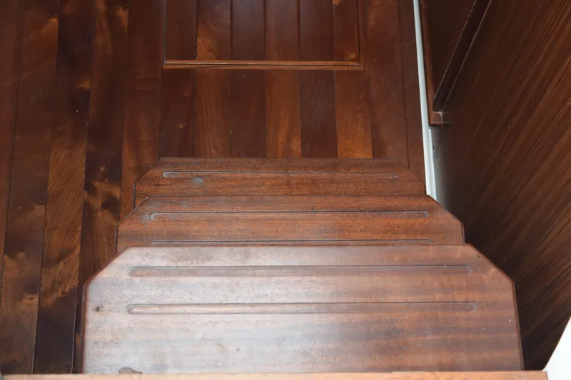 Slide: The Image of Wooden steps inside a 2022 Pursuit OS 355 Offshore boat, showcasing rich brown finish. - 333
