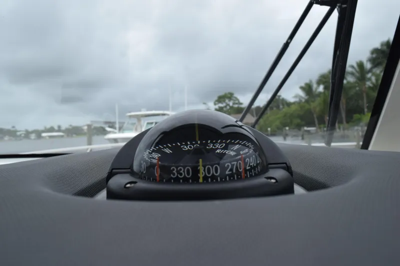 Slide: The Image of Compass on 2022 Pursuit OS 355 Offshore boat dashboard, with cloudy sky and marina view. - 216