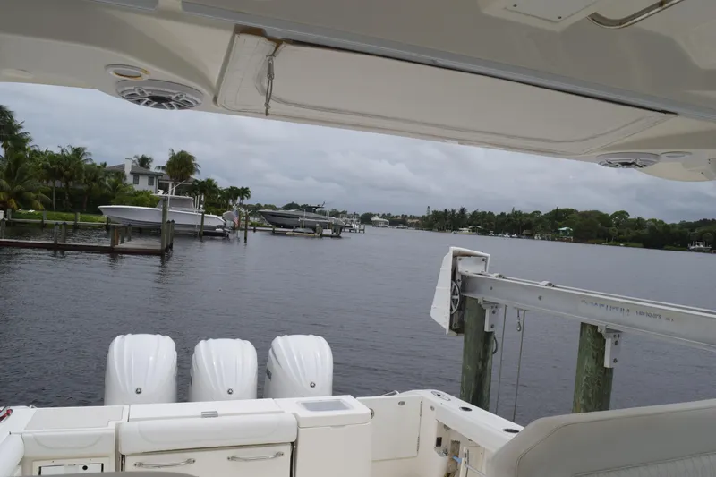 Slide: The Image of 2022 Pursuit OS 355 Offshore boat docked by a scenic waterfront with lush greenery. - 309