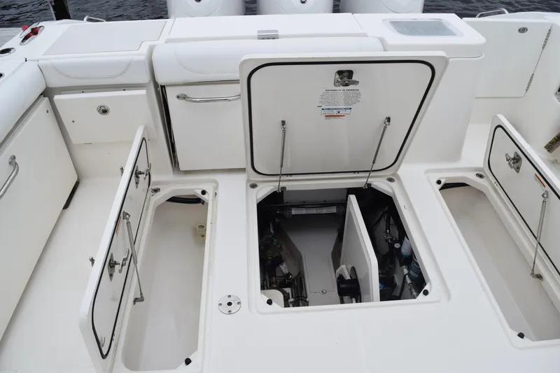 Slide: The Image of 2022 Pursuit OS 355 Offshore boat deck with open storage compartments and engine access. - 144