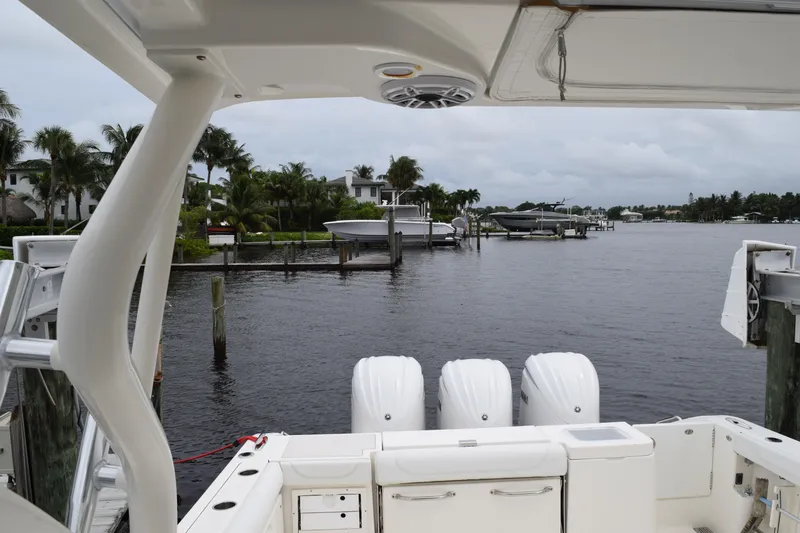 Slide: The Image of 2022 Pursuit OS 355 Offshore boat docked, featuring triple outboard engines, with waterfront view. - 310