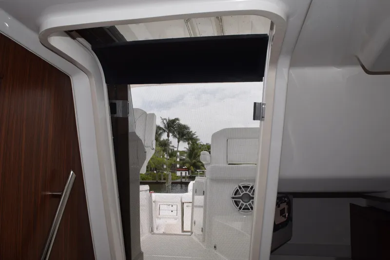 Slide: The Image of 2022 Pursuit OS 355 Offshore cabin entrance with view of deck and palm trees. - 347