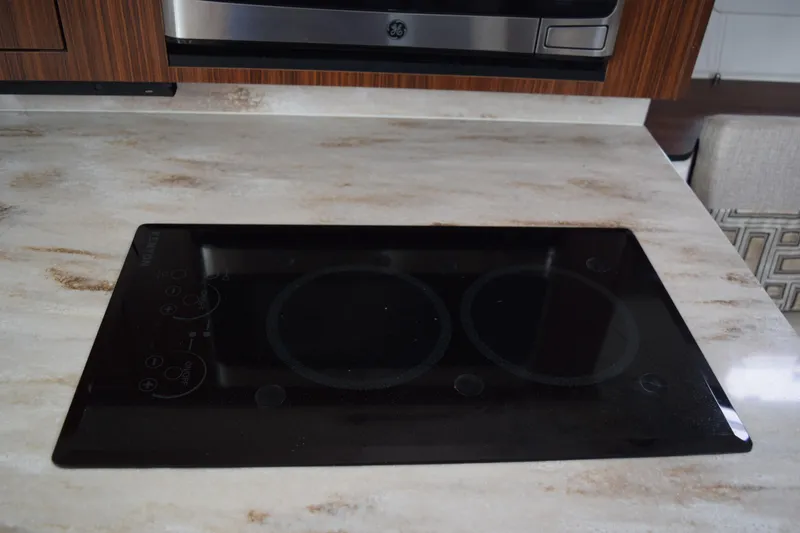 Slide: The Image of Modern induction cooktop on marble countertop in 2022 Pursuit OS 355 Offshore boat kitchen. - 387