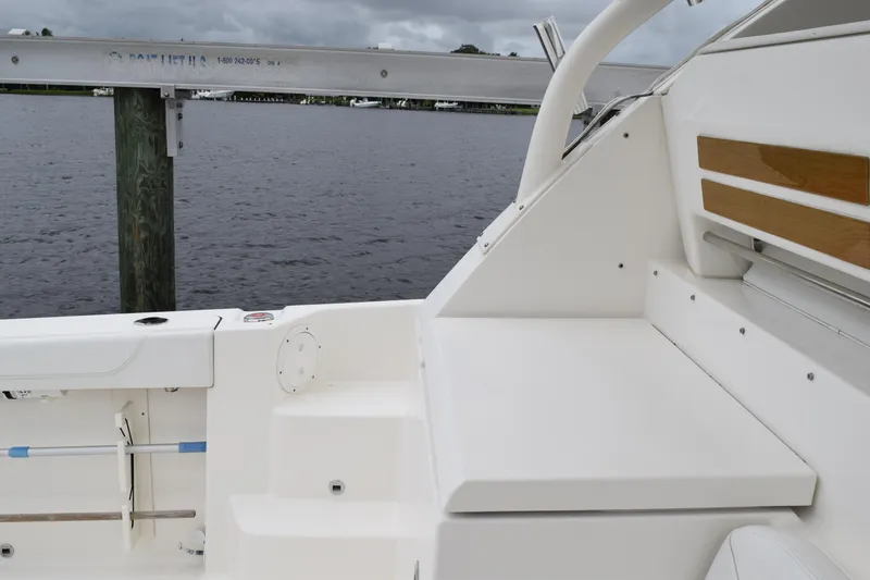 Slide: The Image of 2022 Pursuit OS 355 Offshore boat interior with seating and wooden accents by the water. - 198