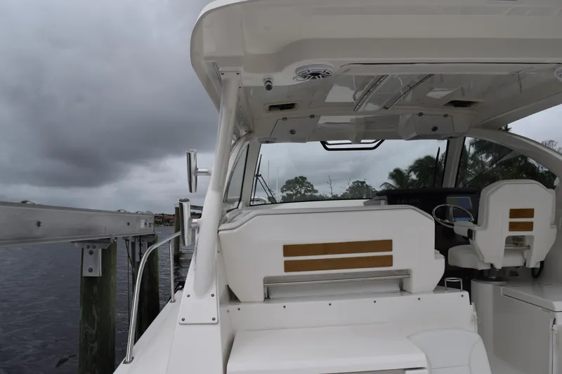Slide: The Image of 2022 Pursuit OS 355 Offshore boat interior with helm and seating, docked under cloudy skies. - 66