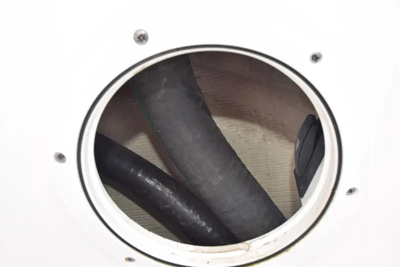 Slide: The Image of Close-up of 2022 Pursuit OS 355 Offshore boat's hose connections inside a circular access panel. - 103