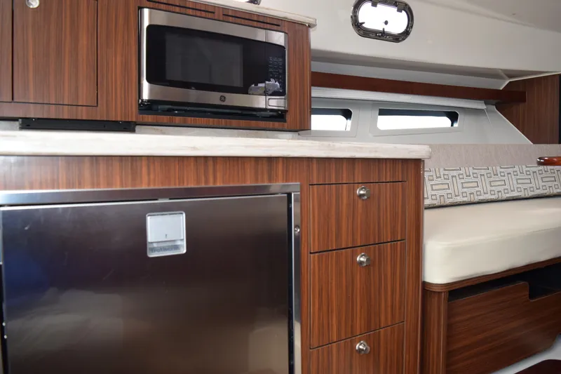 Slide: The Image of 2022 Pursuit OS 355 Offshore interior with microwave, fridge, and seating area. - 418