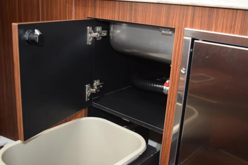 Slide: The Image of 2022 Pursuit OS 355 Offshore interior cabinet with open door and visible plumbing. - 428