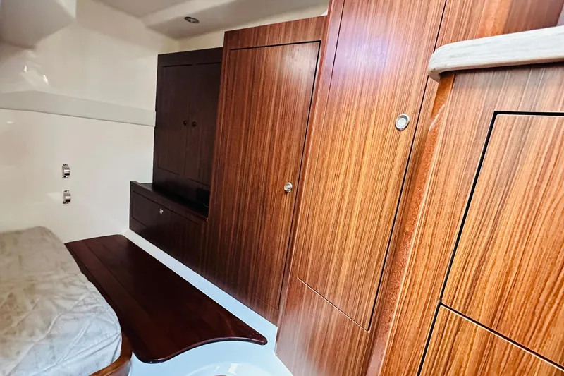 Slide: The Image of 2022 Pursuit OS 355 Offshore cabin interior with wood paneling and bed. - 13