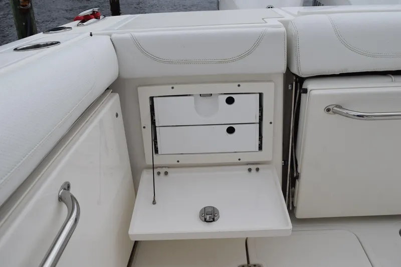Slide: The Image of 2022 Pursuit OS 355 Offshore boat interior storage compartment with white cushioned seating. - 27
