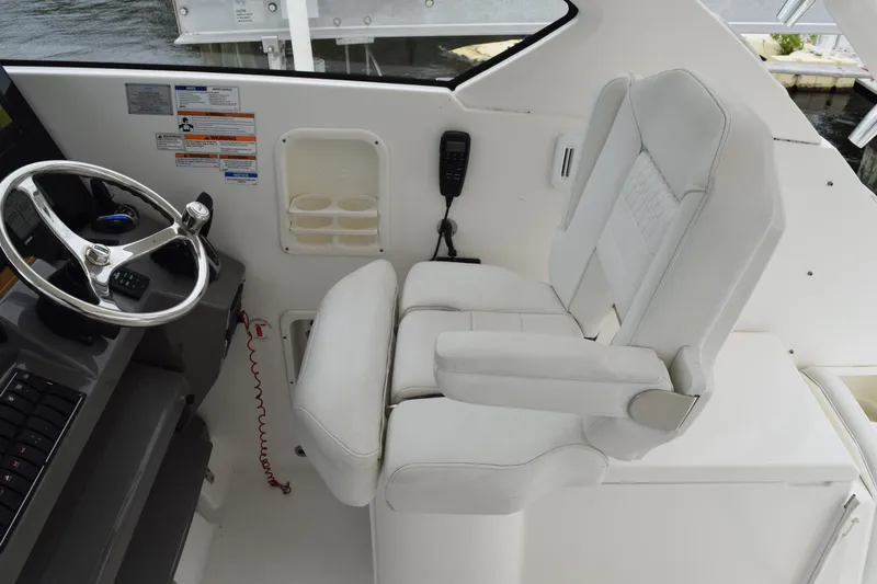 Slide: The Image of 2022 Pursuit OS 355 Offshore helm with white captain's chair and steering wheel. - 247