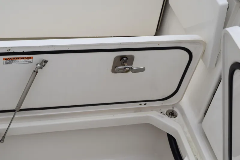 Slide: The Image of 2022 Pursuit OS 355 Offshore storage compartment with warning label and latch. - 141