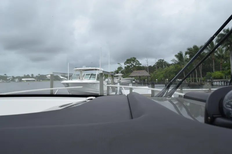 Slide: The Image of 2022 Pursuit OS 355 Offshore boat docked on a cloudy day, surrounded by lush greenery. - 217