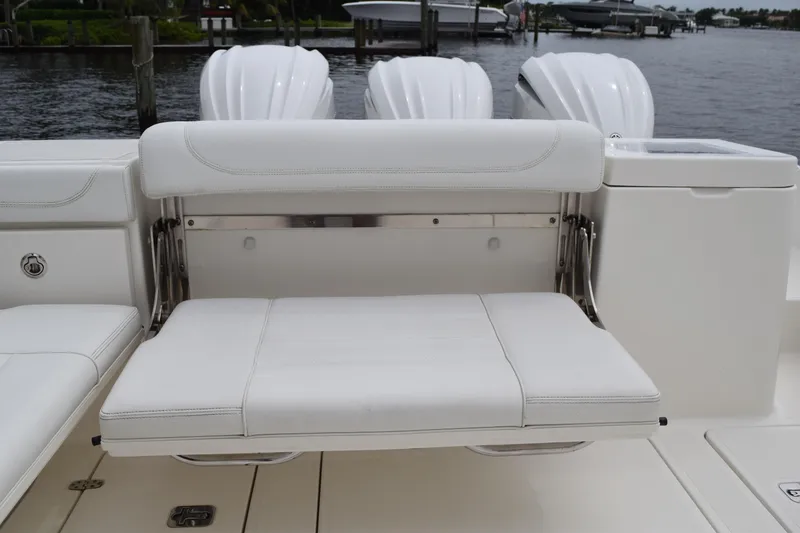 Slide: The Image of 2022 Pursuit OS 355 Offshore boat with white cushioned seating and triple outboard motors. - 49
