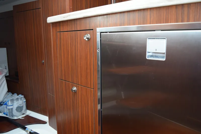 Slide: The Image of 2022 Pursuit OS 355 Offshore interior with wood cabinetry and stainless steel fridge. - 426