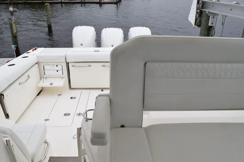Slide: The Image of 2022 Pursuit OS 355 Offshore boat interior with seating and storage, docked by the water. - 231