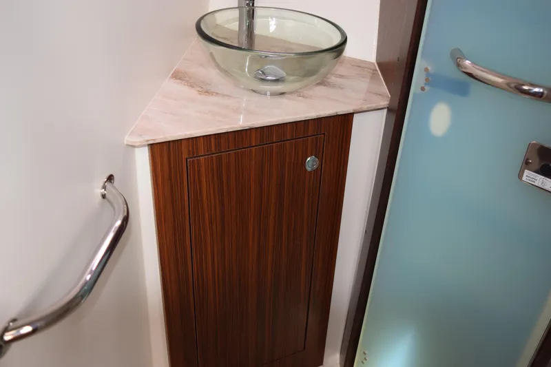 Slide: The Image of 2022 Pursuit OS 355 Offshore bathroom with glass sink and wooden cabinet. - 380