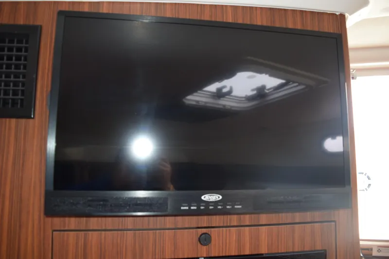 Slide: The Image of Flat-screen TV inside 2022 Pursuit OS 355 Offshore boat, mounted on wood paneling. - 407
