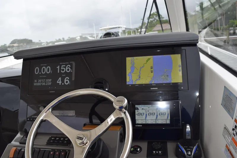 Slide: The Image of 2022 Pursuit OS 355 Offshore boat dashboard with navigation screens and steering wheel. - 303