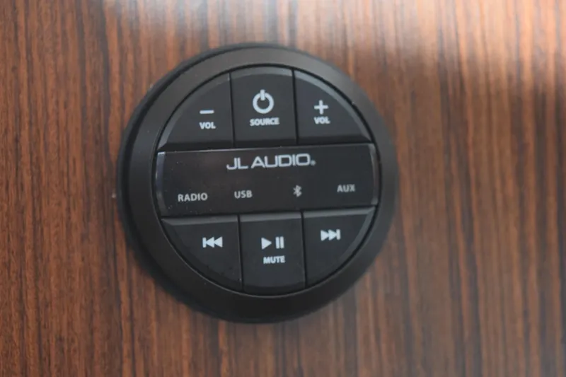 Slide: The Image of JL Audio control panel on 2022 Pursuit OS 355 Offshore boat, mounted on wood surface. - 443