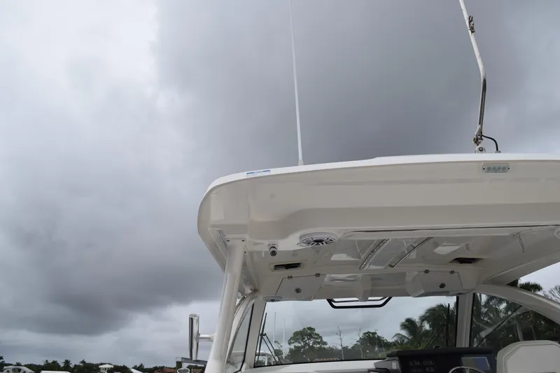 Slide: The Image of 2022 Pursuit OS 355 Offshore boat under cloudy sky, showcasing helm and hardtop. - 67