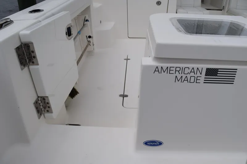 Slide: The Image of 2022 Pursuit OS 355 Offshore boat interior, featuring "American Made" branding and storage compartments. - 74