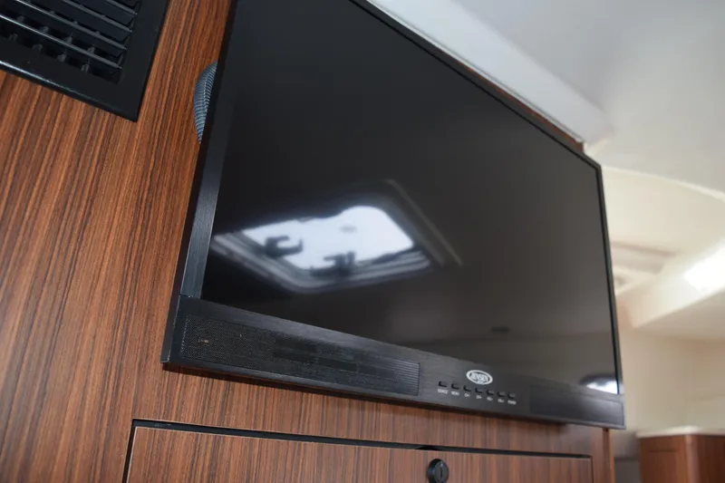 Slide: The Image of Flat-screen TV in 2022 Pursuit OS 355 Offshore boat interior, mounted on wood paneling. - 409