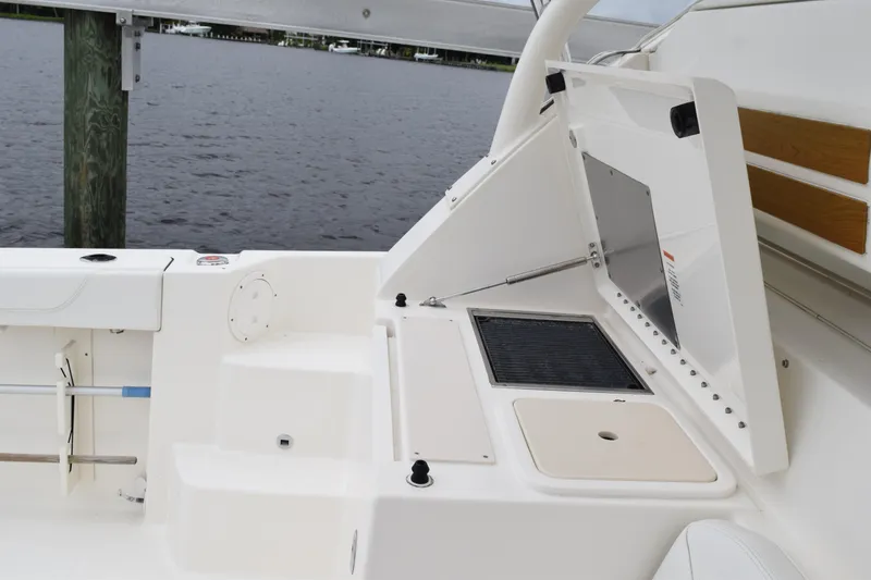 Slide: The Image of 2022 Pursuit OS 355 Offshore boat interior with open storage compartment by the water. - 197