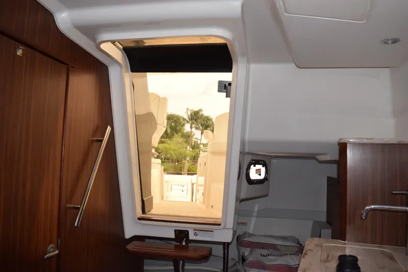Slide: The Image of Interior view of 2022 Pursuit OS 355 Offshore boat, featuring wooden cabinetry and open hatch. - 363