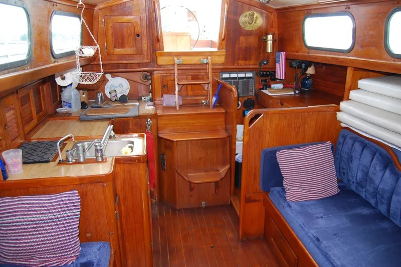 Slide: The Image of Interior of a 1981 Bristol 40 Yawl sailboat with wooden cabinetry and blue seating. - 43