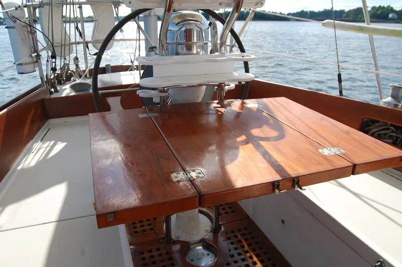 Slide: The Image of 1981 Bristol 40 Yawl cockpit with wooden table, steering wheel, and ocean view. - 19