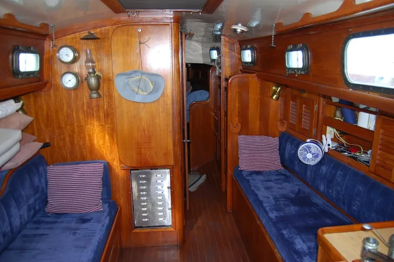 Slide: The Image of Interior of a 1981 Bristol 40 Yawl sailboat with wooden paneling and blue seating. - 42