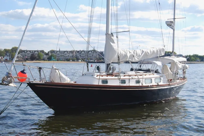 Slide: The Image of 1981 Bristol 40 Yawl sailboat anchored on calm water with scenic shoreline background. - 8
