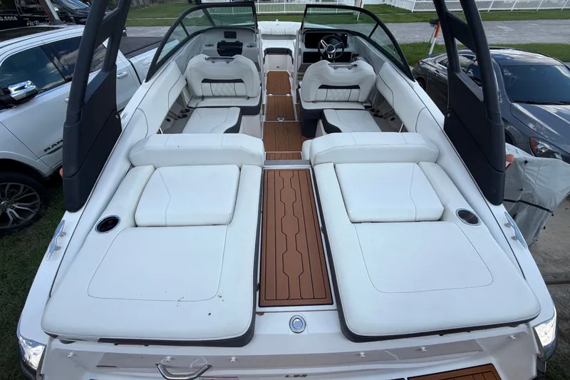 Slide: The Image of 2022 Regal LS2 boat with white seating and wooden deck, parked outdoors. - 13