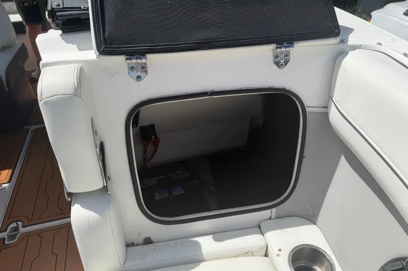 Slide: The Image of Open storage compartment on a 2022 Regal LS2 boat, featuring white upholstery and cup holder. - 49