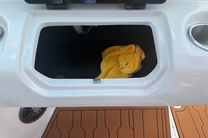Slide: The Image of Open storage compartment on 2022 Regal LS2 boat with yellow cloth inside. - 52