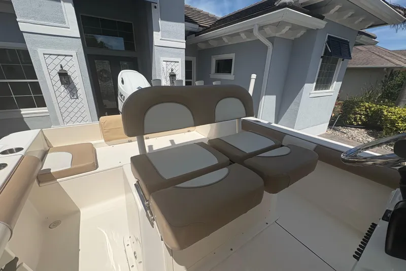 Slide: The Image of 2022 Sea Born LX22 Center Console boat with beige seating, parked near a modern house. - 25