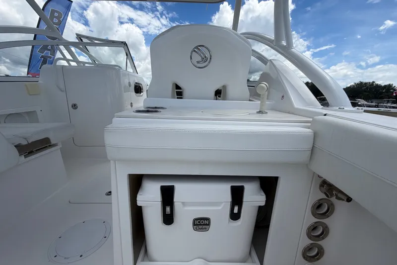 Slide: The Image of The image shows the cockpit of a 2023 Edgewater 248CX Crossover boat with white seating and a cooler. - 18