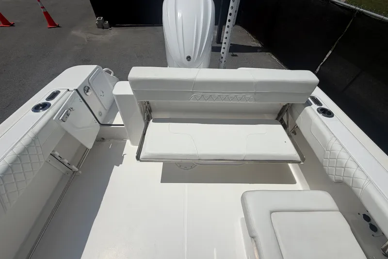 Slide: The Image of 2023 Edgewater 248CX Crossover boat interior with white seating and storage compartments. - 80