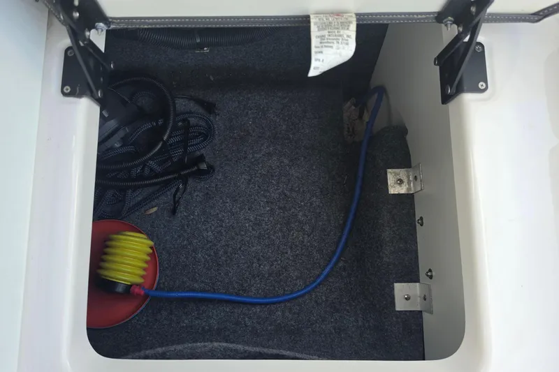 Slide: The Image of Storage compartment of 2022 Yamaha Boats 252SD with coiled hose and accessories. - 29
