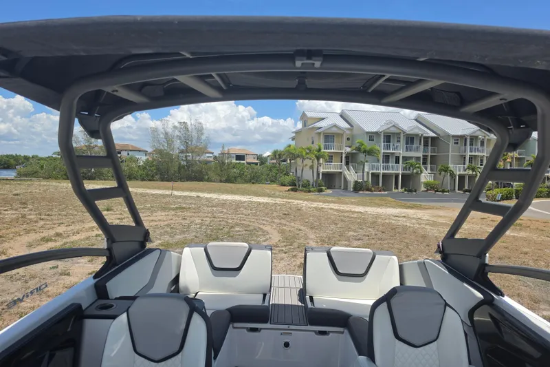 Slide: The Image of 2022 Yamaha Boats 252SD interior with modern seating, overlooking waterfront homes. - 79