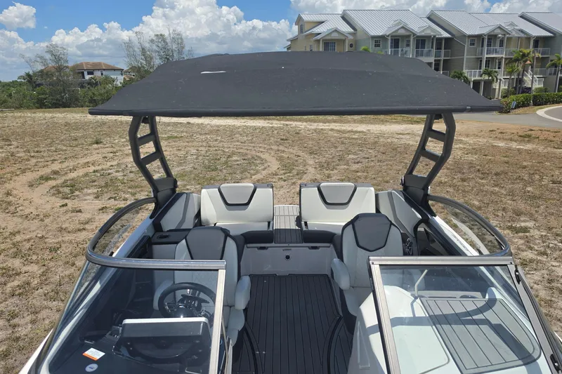 Slide: The Image of 2022 Yamaha Boats 252SD interior with canopy, parked near residential area under blue sky. - 81