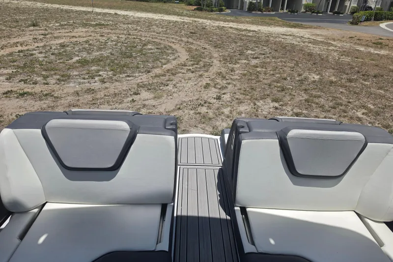 Slide: The Image of 2022 Yamaha Boats 252SD interior seating with gray and white upholstery, outdoor setting. - 74