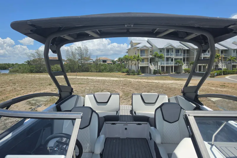Slide: The Image of 2022 Yamaha Boats 252SD interior with modern seating, docked near waterfront homes. - 77
