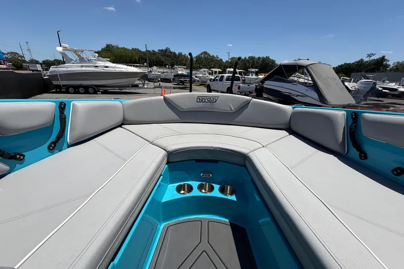 Slide: The Image of 2023 Heyday WTSurf boat interior with gray seating and turquoise accents at a marina. - 87