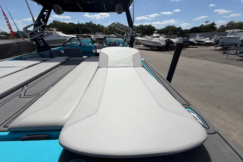 Slide: The Image of 2023 Heyday WTSurf boat interior with sun pad and seating, docked under clear skies. - 49